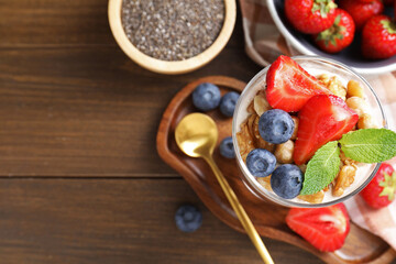 Delicious chocolate pudding with chia seeds, nuts and berries in glass on wooden table, flat lay....