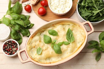 Tasty vegetarian lasagna and ingredients on wooden table, flat lay