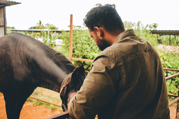 Man gently petting a black and white horse in a rural Indian setting
