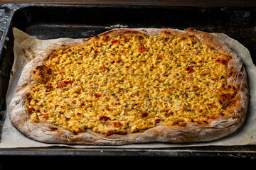 Homemade freshly cooked pizza or pie with cottage cheese, tomatoes, cheese and herbs on a metal...