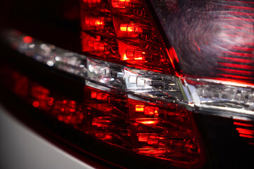 Close-up of modern red and white LED car tail light with geometric internal structure. Macro shot...