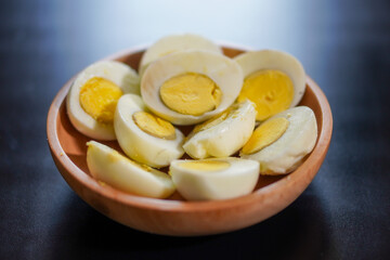 Several boiled eggs that have been halved in a wooden bowl