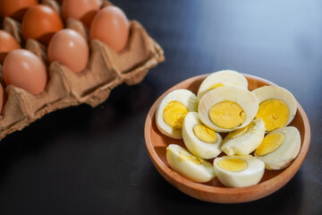 A pile of halved hard boiled eggs in a wooden bowl with a few whole eggs on top of the egg carpet