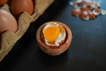 Closeup, One half boiled egg complete with several whole eggs on top of the egg carpet and egg shells