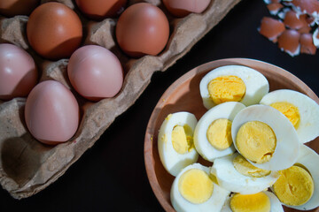 A pile of halved hard boiled eggs in a wooden bowl with a few whole eggs on top of the egg carpet...