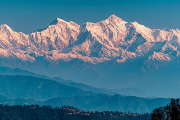 a mountain range with a river running through it and snow capped mountains in the background, with a blue sky