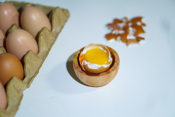 Closeup, One half boiled egg complete with several whole eggs on top of the egg carpet and egg...