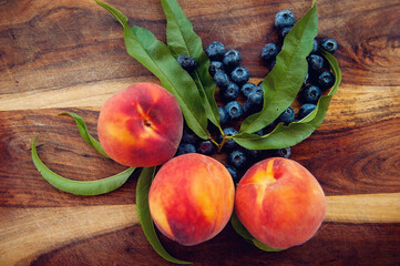 Overhead view of fresh peaches and blueberries on  wooden chopping board