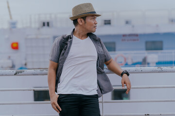 Asian man in backpack standing on the ship enjoy solo traveling a beautiful view on the ocean....