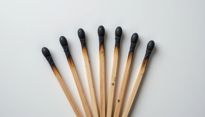 Burnt matches arranged on white surface, aftermath of striking flames concept