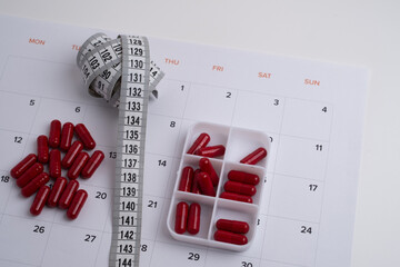 Measuring tape and tablets, vitamins on a light background with space for text. Concept of losing...