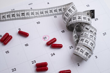 Measuring tape and tablets, vitamins on a light background with space for text. Concept of losing...