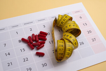 Measuring tape and tablets, vitamins on a light background with space for text. Concept of losing...