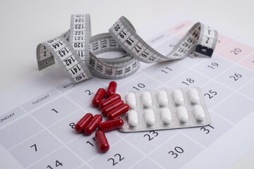 Measuring tape and tablets, vitamins on a light background with space for text. Concept of losing...