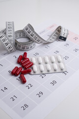 Measuring tape and tablets, vitamins on a light background with space for text. Concept of losing...