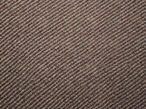 Photorealistic detailed image of a uniform twill weave pattern, cotton threads, subtle diagonal ridges, starkly lit on a background with a patchwork of complementary colors, focus on material structur