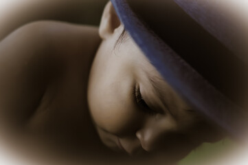 A baby boy close up photo, with him wearing a hat