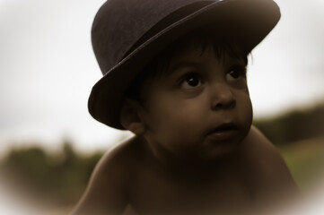 Curious baby boy with a hat looking up at something off camera