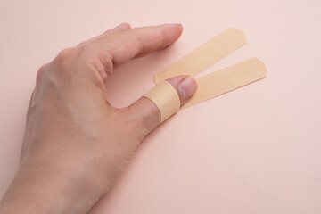 Female hand with medical adhesive plaster close-up. Adhesive plaster on damaged skin. First aid for wounds and cuts