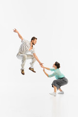Swing dancers are captured mid-air in vintage attire against a white background. Concept of retro dance enthusiasm and joyful movement.