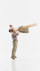A man lifts a woman in a retro dance pose against a white background. Concept of timeless love and...