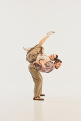 A dynamic retro dance performance showcases a couple in vintage attire executing an acrobatic pose...