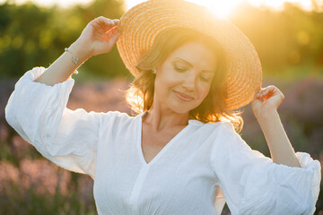 Beautiful woman enjoying summer breeze in lavender field. Portrait of blonde in sunlight....