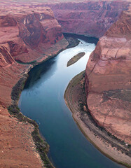 Dramatic aerial view of a winding river cutting through red rock canyons. Captures natures power and beauty. Great for travel, adventure, and conservation themes.