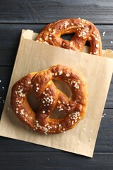 Tasty pretzels with salt on dark wooden table, top view