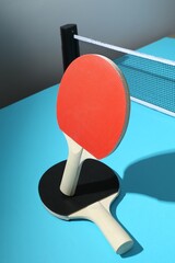 Ping pong rackets and net on light blue table