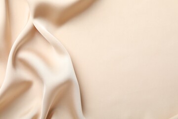 Crumpled beige silk fabric as background, top view. Space for text