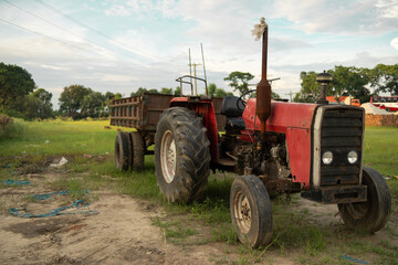 Obraz premium A red tractor with a trailer parked in a field