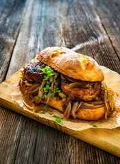 Takeaway sandwich with fried minced cutlets and caramelized onion on wooden table