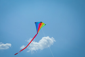 Colorful kite flying in blue sky, low angle view