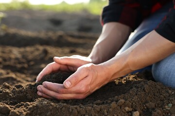 Man taking pile of soil in field, closeup