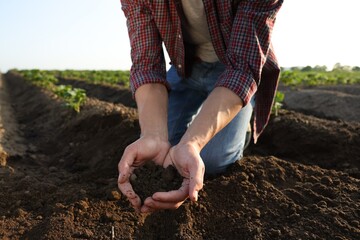 Man holding pile of soil in field, closeup