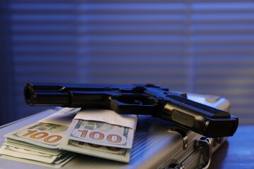 Mafia and criminal world. Briefcase with money and gun indoors, closeup