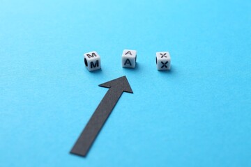 Word Max made of beads with letters and arrow pointing at it on light blue background, closeup