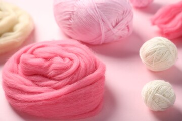 Felting wool and knitting yarn on pink background, closeup