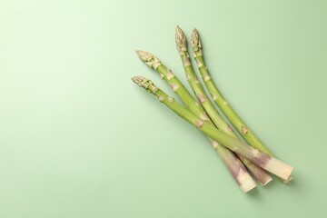 Fresh ripe raw asparagus on green background, top view. Space for text