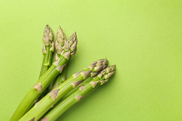 Fresh ripe raw asparagus on green background, top view. Space for text