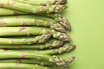 Fresh ripe raw asparagus on green background, closeup