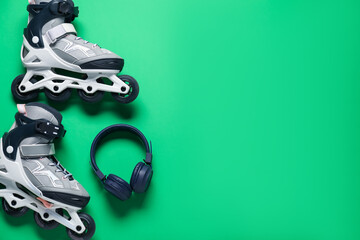 Pair of roller skates and headphones on green background, top view. Space for text