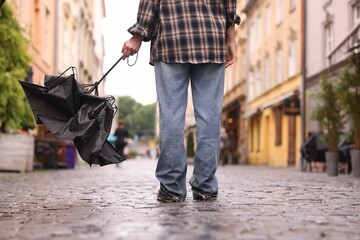 Woman with broken umbrella on wet pavement outdoors, closeup