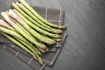 Fresh raw asparagus spears on black table, top view. Space for text