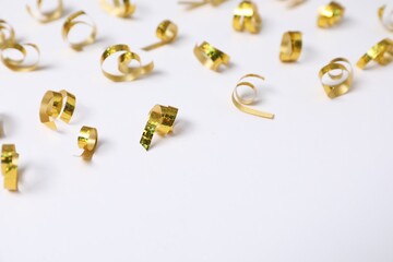 Shiny golden party streamers on white background, closeup. Space for text