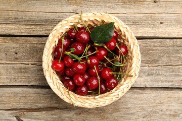 Fresh wet cherries in wicker basket on wooden table, top view