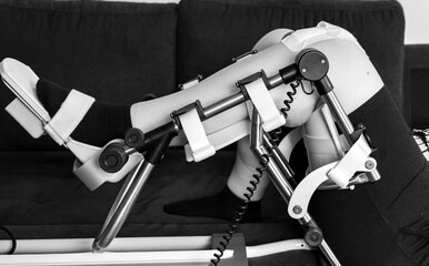 Physiotherapy at home: patient with knee orthosis and therapy device