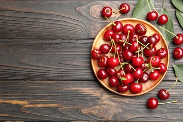 Fresh ripe cherries on black wooden table, flat lay. Space for text