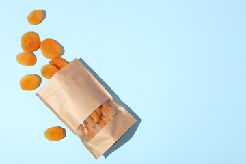 Zipper stand-up pouch with dried apricots on light blue background, flat lay. Mockup for design